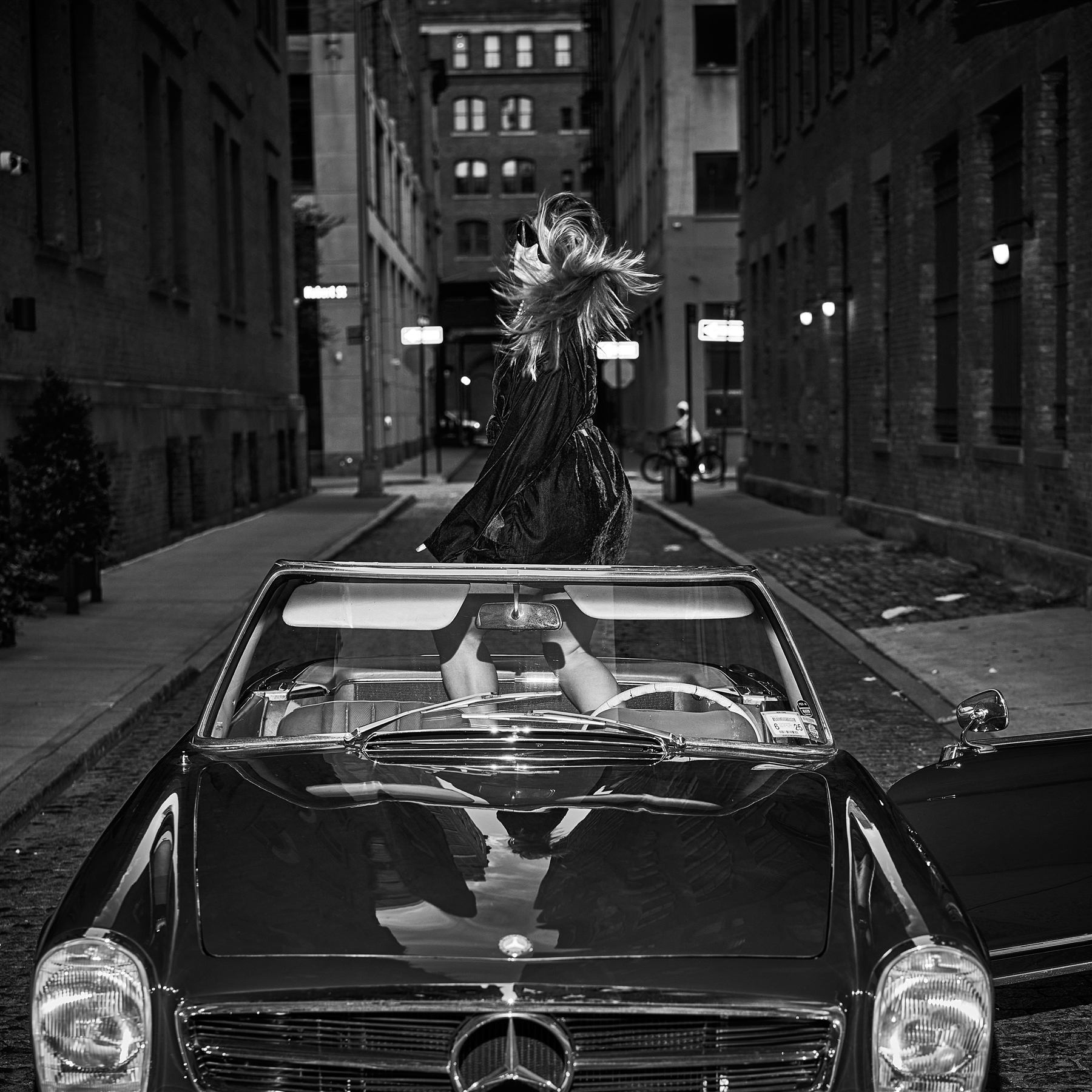A model mid hair-flip behind the vintage Mercedes on a cobblestone street