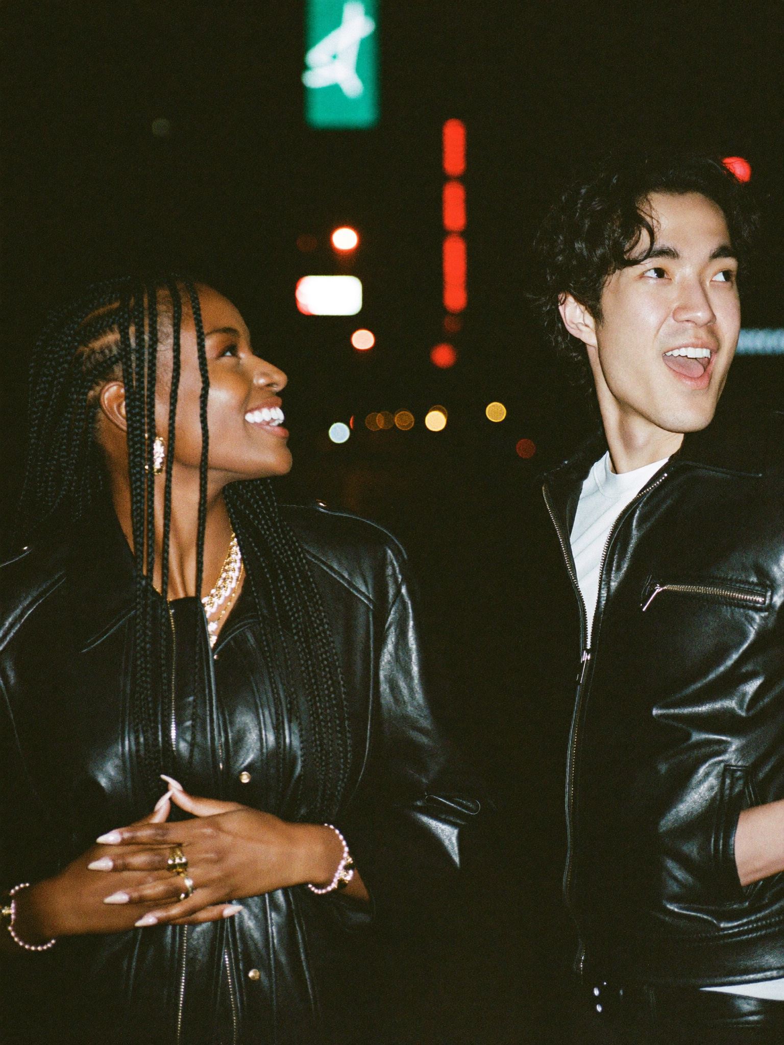 Two friends in leather jackets on a neon-lit New York street at night