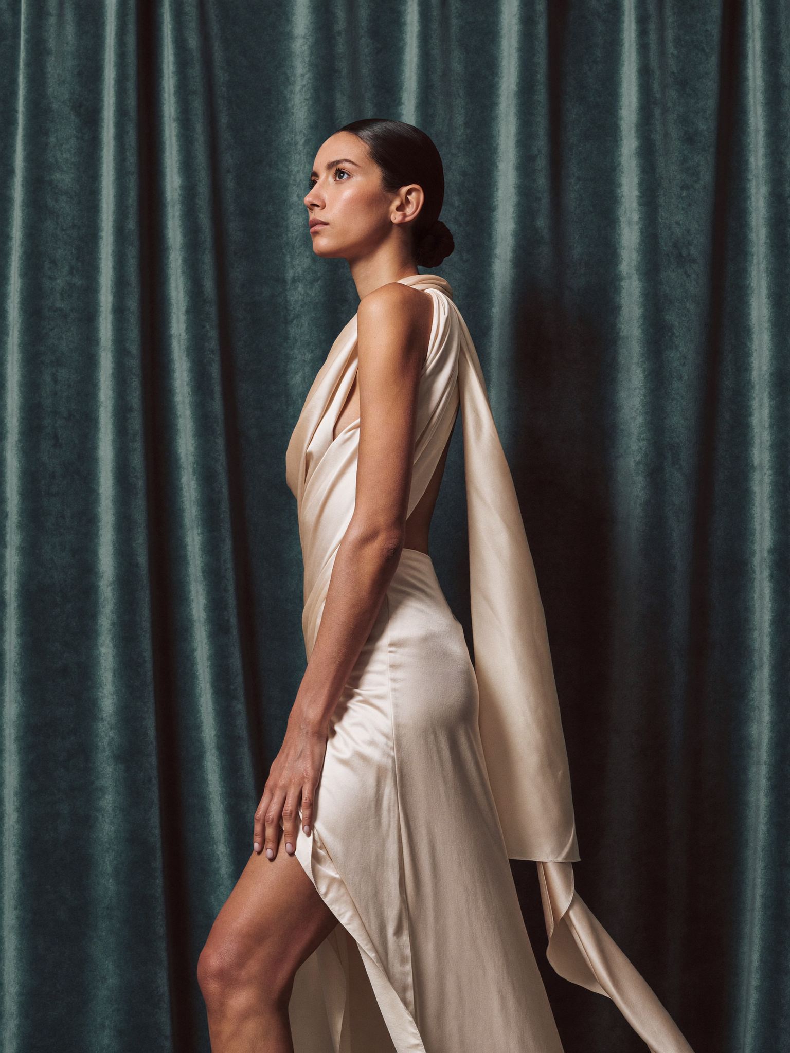 A model in cream silk against deep green velvet