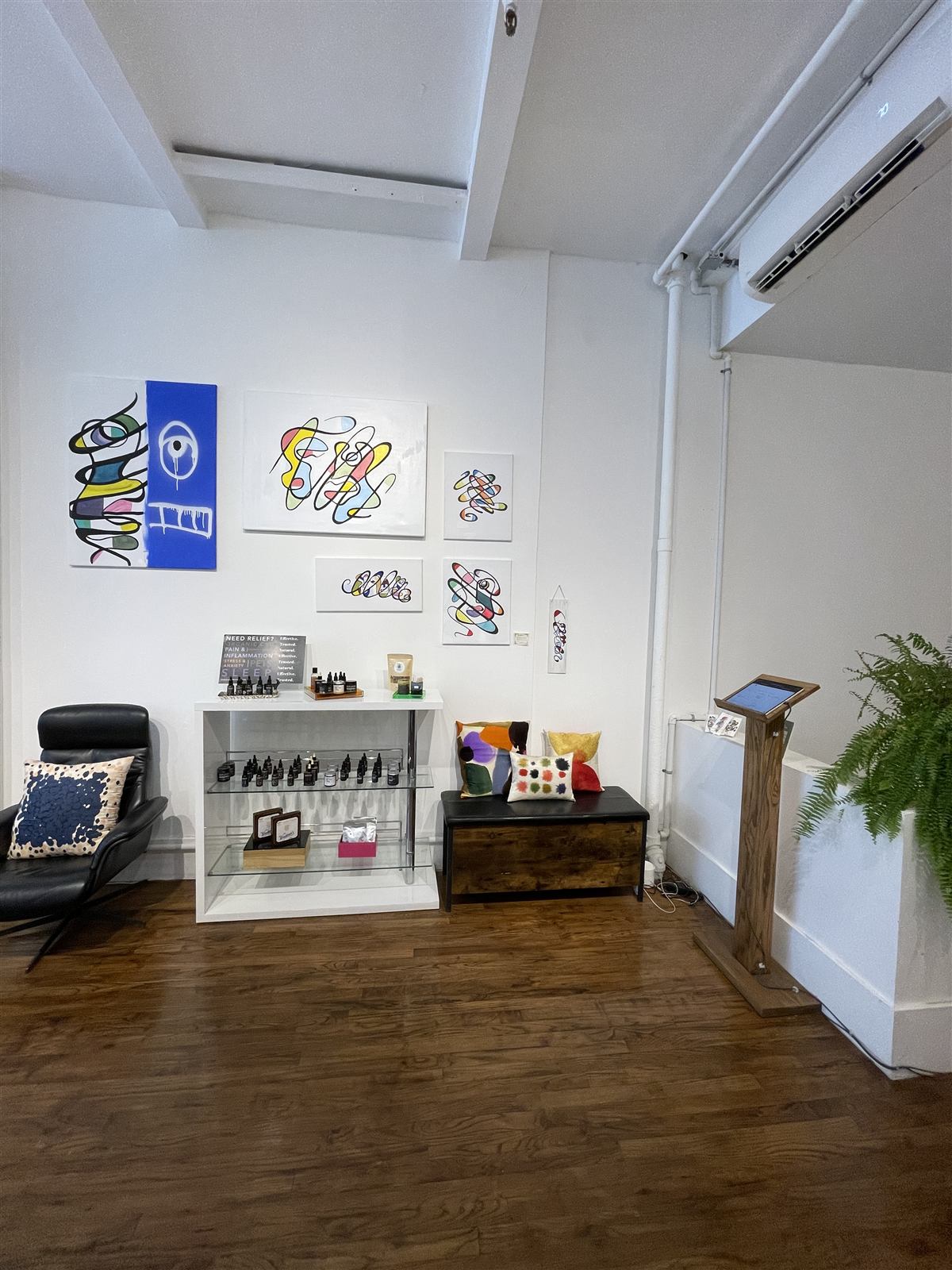 Colourful original artwork hung gallery-style on the white walls of the reception area