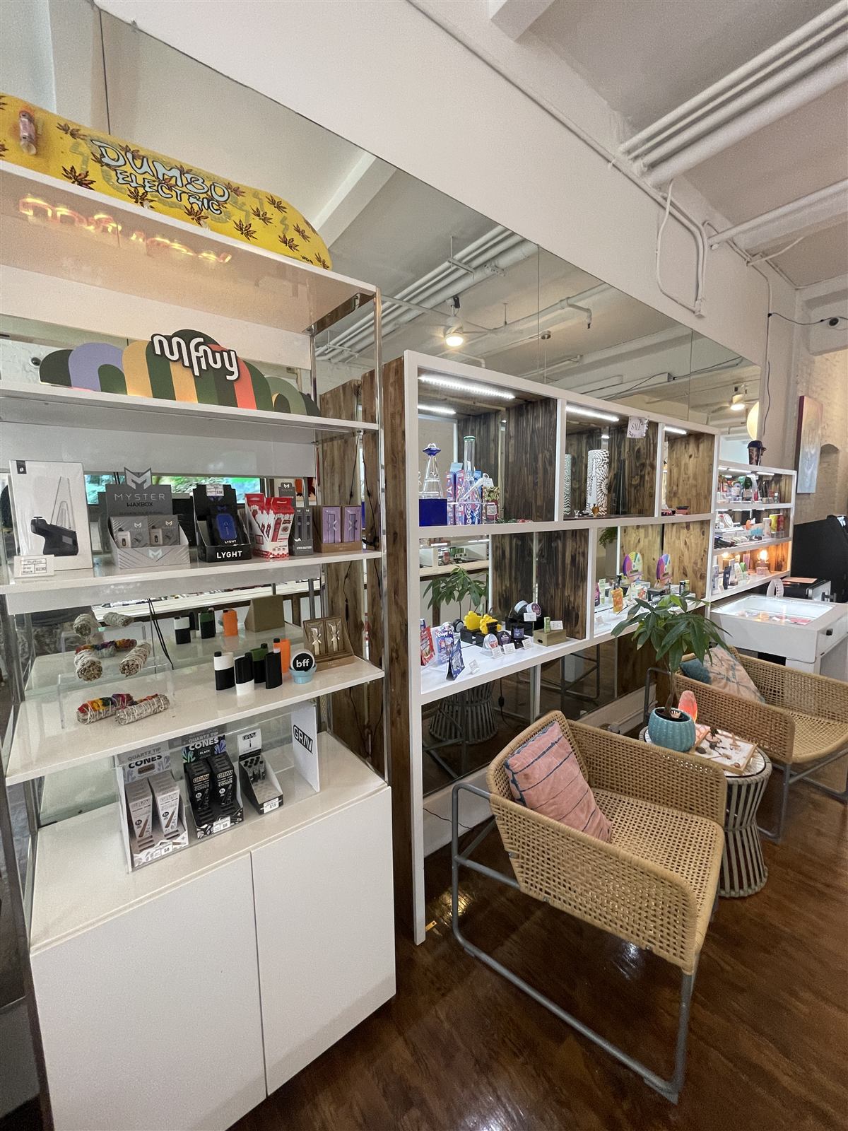 The dispensary floor at the back of the store — white display cases, wicker chairs and warm wood floors