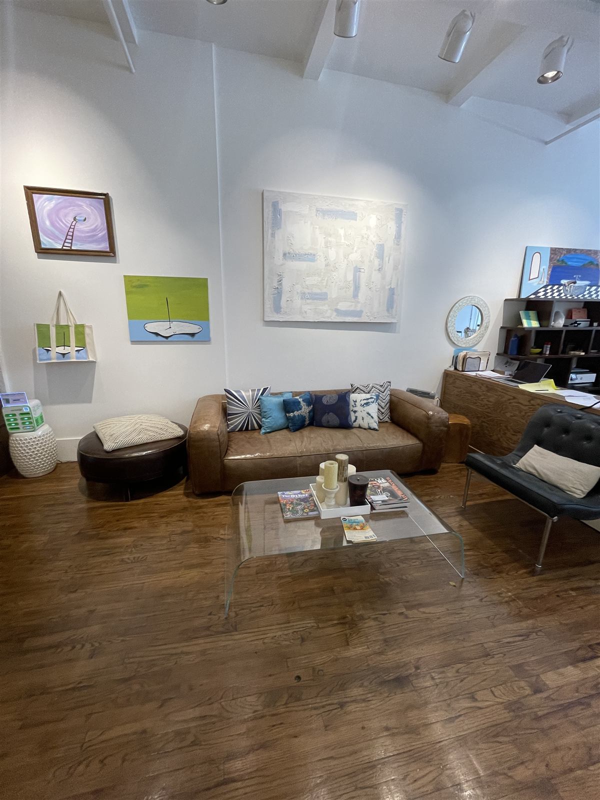 The reception lounge at 122 E 25th Street — a leather sofa with blue cushions and original artwork on white gallery walls